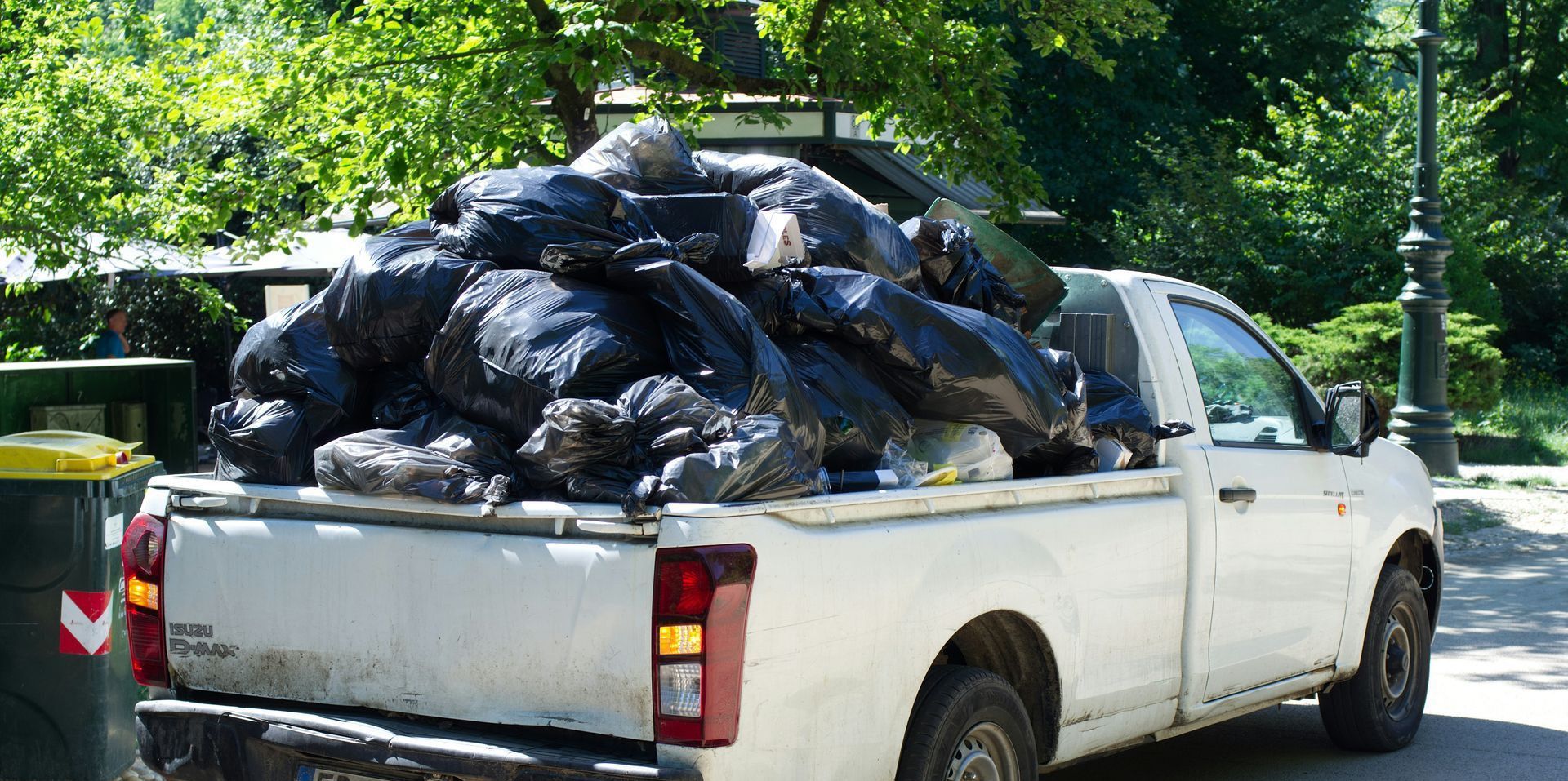 A white pickup truck overloaded with black trash bags